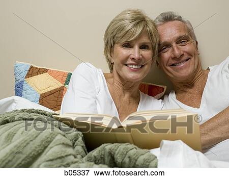 Stock Photo - Mature couple in bed reading. Fotosearch