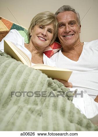 Stock Photograph - Mature couple in bed reading. Fotosearch