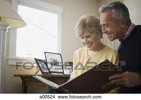 Mature couple looking at photo album View Large Photo Image Picture - Mature couple looking at photo album. Fotosearch