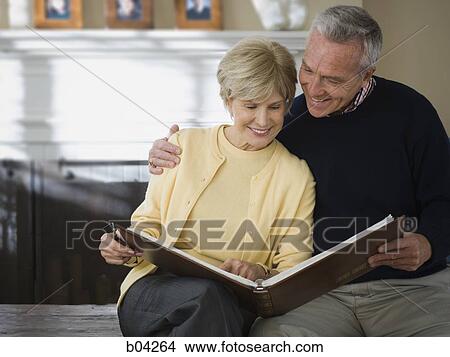 Mature couple looking at photo album View Large Photo Image Picture - Mature couple looking at photo album. Fotosearch