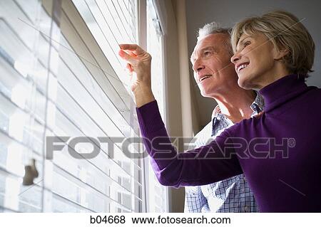 Mature couple looking through blinds View Large Photo Image Stock Photo - Mature couple looking through blinds. Fotosearch