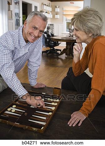 Stock Image - Mature couple playing backgammon. Fotosearch