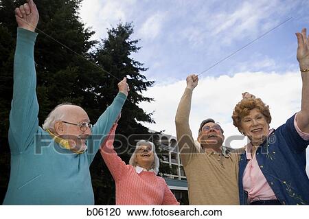 Stock Image - Mature couples outside cheering. Fotosearch