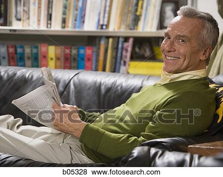 Mature man lying on sofa with newspaper View Large Photo Image Stock Photo - Mature man lying on sofa with newspaper. Fotosearch