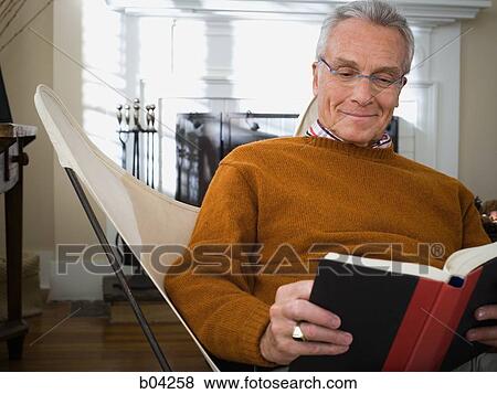 Mature man sitting in chair reading View Large Photo Image Stock Photo - Mature man sitting in chair reading. Fotosearch