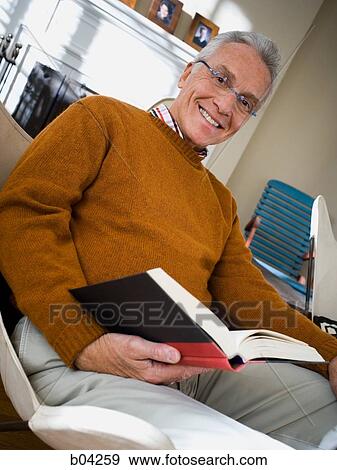 Mature man sitting in chair reading View Large Photo Image Stock Photo - Mature man sitting in chair reading. Fotosearch
