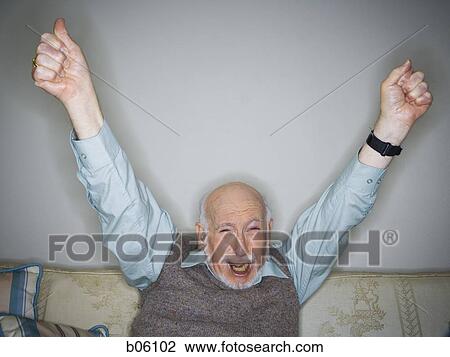 Mature man sitting on a couch cheering View Large Photo Image Stock Image - Mature man sitting on a couch cheering. Fotosearch