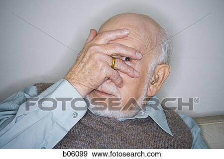 Mature man sitting on a couch covering his eyes View Large Photo Image Stock Photo - Mature man sitting on a couch covering his eyes. Fotosearch