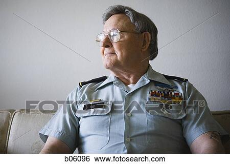 Stock Photograph - Mature man sitting on a couch in a military uniform. Fotosearch
