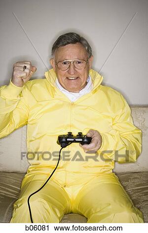 Mature man sitting on a couch playing a videogame View Large Photo Image Stock Image - Mature man sitting on a couch playing a videogame. Fotosearch