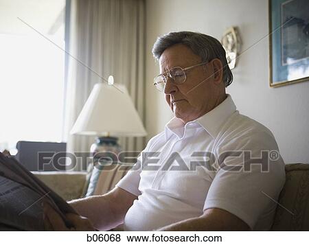 Mature man sitting on a couch reading the paper View Large Photo Image Stock Photo - Mature man sitting on a couch reading the paper. Fotosearch