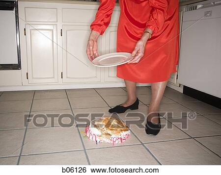 Stock Photograph - Mature woman dropping a birthday cake. Fotosearch