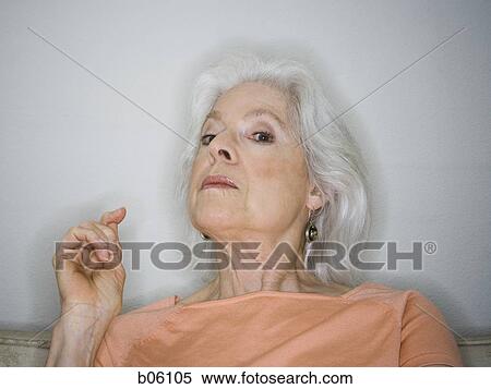 Stock Photography - Mature woman sitting on a couch. Fotosearch