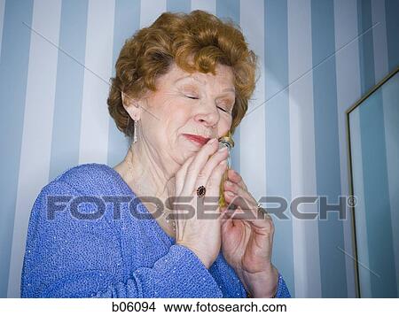 Mature woman smelling perfume View Large Photo Image Picture - Mature woman smelling perfume. Fotosearch