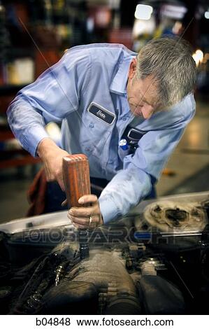 Stock Photo - Mechanic fixing car with drill. Fotosearch