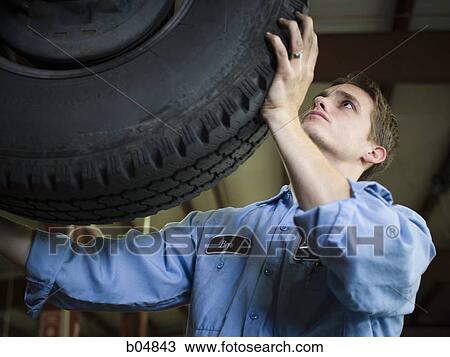 Mechanic holding up car tire View Large Photo Image Stock Image - Mechanic holding up car tire. Fotosearch