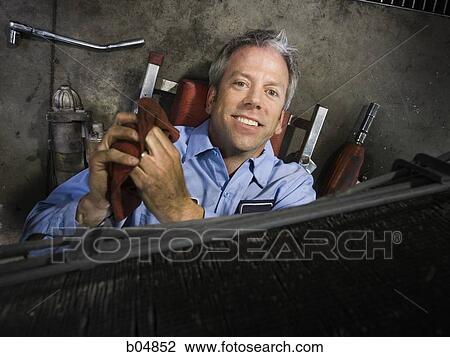 Mechanic under car smiling View Large Photo Image Stock Image - Mechanic under car smiling. Fotosearch