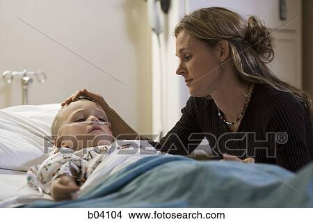 Mother stroking son's head in hospital bed View Large Photo Image Picture - Mother stroking son's head in hospital bed. Fotosearch