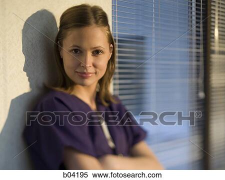 Stock Photography - Nurse leaning on wall with arms crossed. Fotosearch
