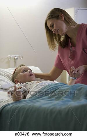 Nurse talking to young boy in hospital bed View Large Photo Image Stock Photo - Nurse talking to young boy in hospital bed. Fotosearch