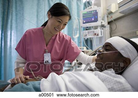 Stock Image - Nurse talking with boy in hospital bed. Fotosearch