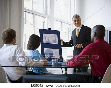 Stock Image - Older Businessman making presentation at meeting. Fotosearch