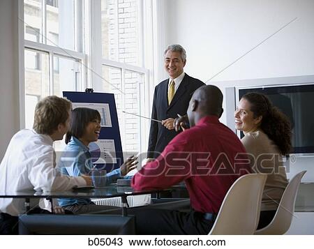 Stock Image - Older Businessman making presentation at meeting. Fotosearch
