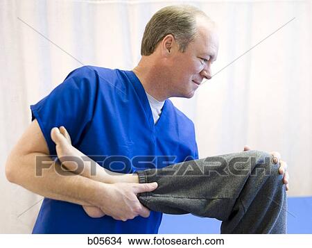 Physical therapist holding leg of a patient View Large Photo Image Picture - Physical therapist holding leg of a patient. Fotosearch