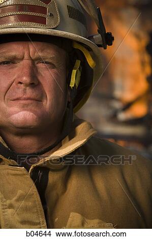 Picture - Portrait of a firefighter with fire in background. Fotosearch