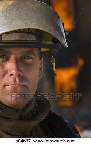 Stock Photo - Portrait of a firefighter with fire in background. Fotosearch