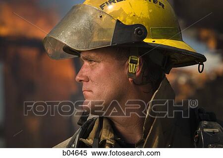 Stock Photography - Portrait of a firefighter with fire in background. Fotosearch