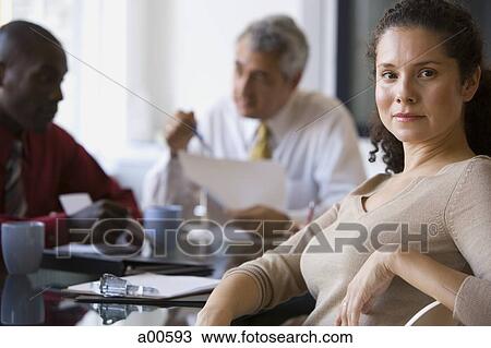 Stock Image - Portrait of woman sitting in business meeting. Fotosearch