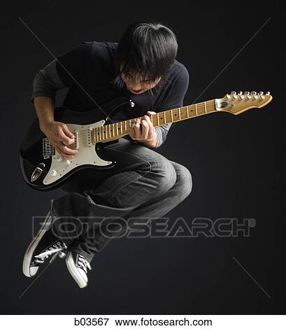 Stock Photo - Portrait of young man playing electric guitar. Fotosearch
