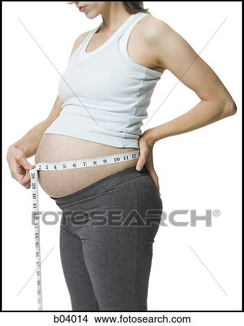 Pregnant woman measuring belly View Large Photo Image Picture - Pregnant woman measuring belly. Fotosearch