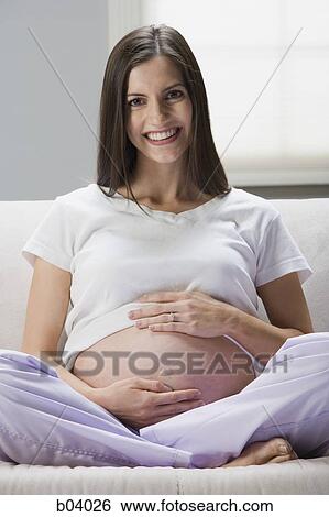 Pregnant woman sitting on sofa smiling View Large Photo Image Stock Photograph - Pregnant woman sitting on sofa smiling. Fotosearch