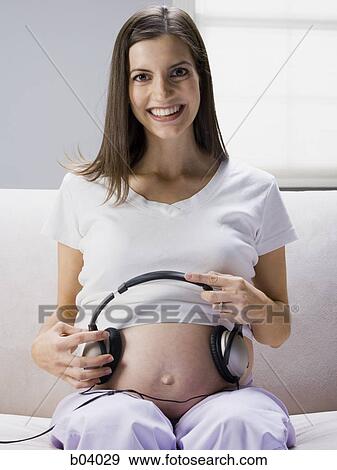 Pregnant woman sitting with headphones on belly View Large Photo Image Stock Photo - Pregnant woman sitting with headphones on belly. Fotosearch