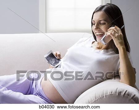 Stock Image - Pregnant woman talking on cordless phone. Fotosearch