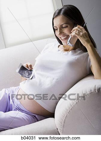 Stock Image - Pregnant woman talking on cordless phone. Fotosearch