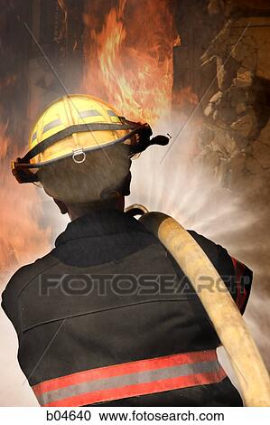 Stock Image - Rear View of a firefighter with hose. Fotosearch