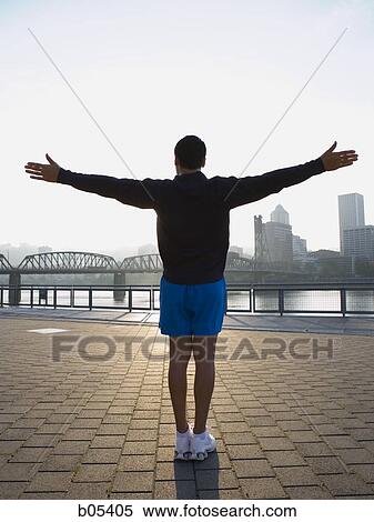 Rear view of male jogger with arms up in city View Large Photo Image Stock Photography - Rear view of male jogger with arms up in city. Fotosearch