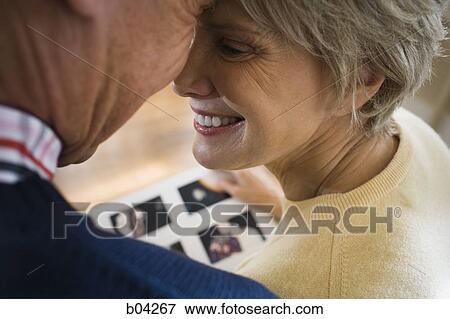Rear view of mature couple with photo album View Large Photo Image Stock Photo - Rear view of mature couple with photo album. Fotosearch