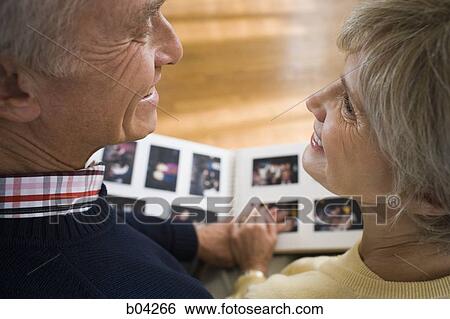 Rear view of mature couple with photo album View Large Photo Image Stock Photograph - Rear view of mature couple with photo album. Fotosearch