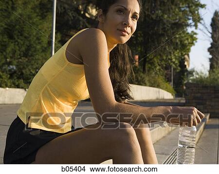 Side profile of woman sitting outdoors with bottled water View Large Photo Image Picture - Side profile of woman sitting outdoors with bottled water. Fotosearch