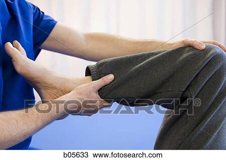 Therapist holding male leg View Large Photo Image Stock Image - Therapist holding male leg. Fotosearch