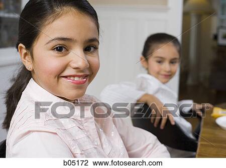 Two girls sitting at table smiling View Large Photo Image Stock Image - Two girls sitting at table smiling. Fotosearch