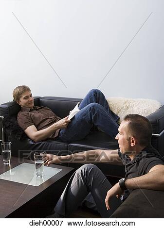Stock Photo - Two men on sofas with glasses of water. Fotosearch