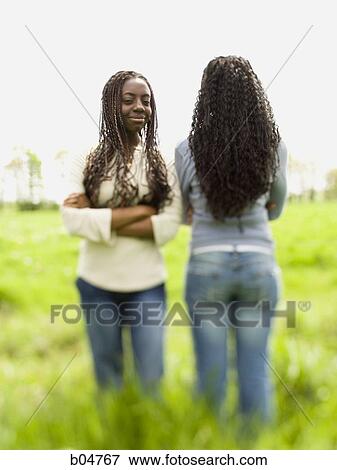 Two women standing in a field View Large Photo Image Stock Photo - Two women standing in a field. Fotosearch
