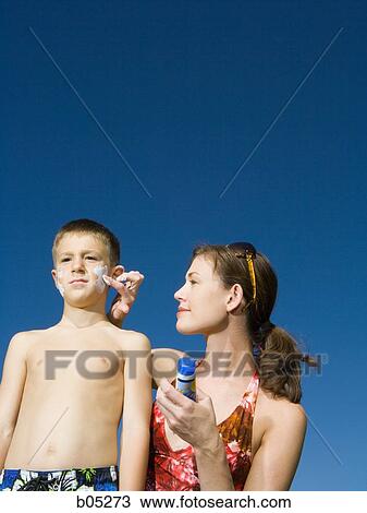 Woman applying sunscreen lotion to boy's face View Large Photo Image Stock Image - Woman applying sunscreen lotion to boy's face. Fotosearch