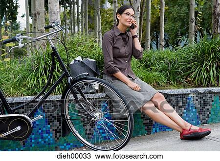 Woman beside bicycle talking on cell phone View Large Photo Image Stock Image - Woman beside bicycle talking on cell phone. Fotosearch