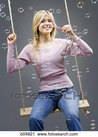 Woman blowing bubbles on swing View Large Photo Image Stock Image - Woman blowing bubbles on swing. Fotosearch